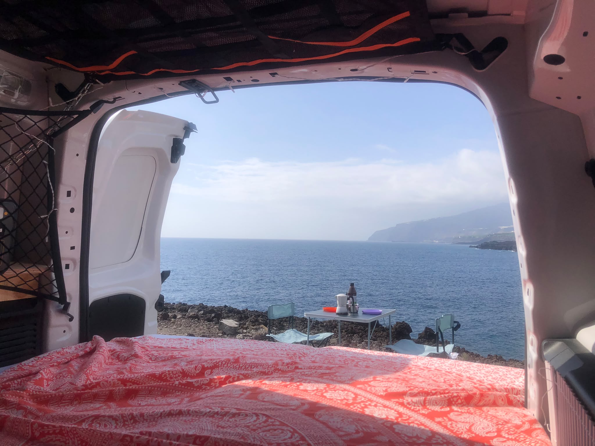 Puertas traseras abiertas con mesa de camping frente al mar en La Palma